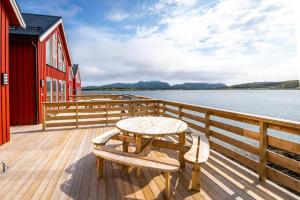 a wooden deck with a table and chairs on the water at Lofoten Rorbu Lodge in Offersøya