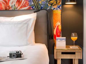 a bed with a camera and a glass of wine at Swissôtel Amsterdam in Amsterdam