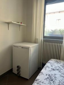 a small white refrigerator in a room with a window at Pasa da sí in Alba