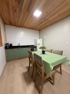 a kitchen with a table and chairs and a kitchen with a refrigerator at Cabana Raízes da Mata - Hidro e Natureza in São Joaquim