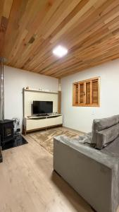 a living room with a couch and a flat screen tv at Cabana Raízes da Mata - Hidro e Natureza in São Joaquim