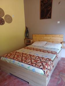 a bed in a bedroom with a wooden headboard at Jedd Palace in Kpannou