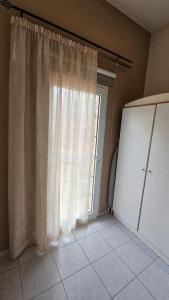a kitchen with a large window with curtains at Camvas Apartments in Panormos Kalymnos +2 photos