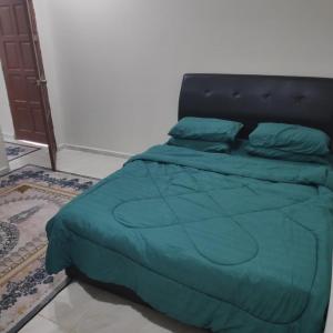 a bed with a blue comforter in a bedroom at Desa Landak Chalet in Jertih