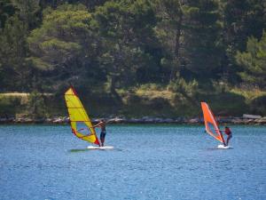 three people are windsurfing on a lake at Beach studio KATE - Wake up to the sea, terrace, garden & parking, Murter - Dalmatia in Murter