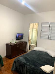 a bedroom with a bed and a television on a dresser at kitnet 101 mob in Tatuí
