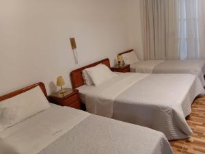 a hotel room with two beds with white sheets at Hotel guido palace in Buenos Aires