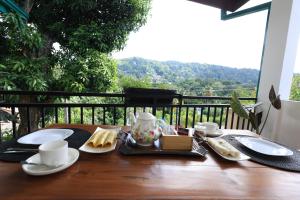 a table with a breakfast of bread and coffee on a balcony at Mino Villa Kandy in Kandy