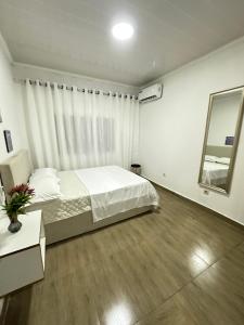 a white bedroom with a bed and a mirror at Cintya Maria in Camama