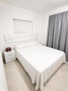 a white bedroom with two beds and a window at Apartamento Benidorm primera linea in Benidorm