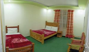 a small bedroom with two beds and a chair at Homeland Hotel and Resort in Burāwai