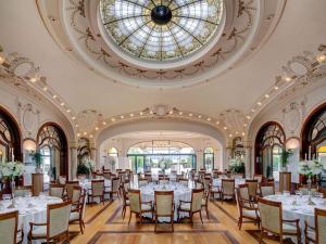 a ballroom with tables and chairs and a stained glass window at Fairmont Le Montreux Palace in Montreux
