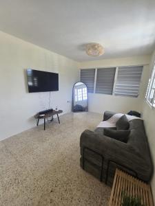 a living room with a couch and a flat screen tv at Casa Bali Tropical Escape in Vega Alta