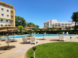a pool with chairs and umbrellas next to a building at Alegria in Varna City