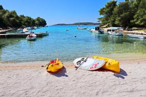 two kayaks on a beach with boats in the water at Villa Green Bay in Vela Luka
