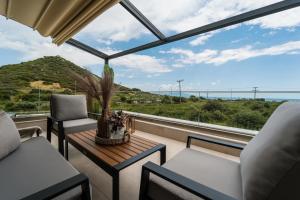 a balcony with a table and chairs and a view of the ocean at Ammosphere in Nea Peramos