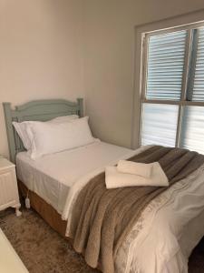 a bedroom with a bed with a blanket and a window at At Let Se Plek in Jeffreys Bay +11 photos