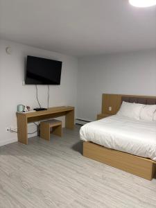 a hotel room with a bed and a flat screen tv at Rundle Inn and Suites in Edmonton