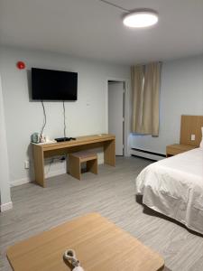 a hotel room with a bed and a desk with a television at Rundle Inn and Suites in Edmonton