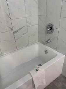 a white bath tub with a shower with a towel at Rundle Inn and Suites in Edmonton