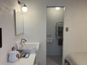 a white bathroom with a sink and a mirror at Cafe & Stay Flyway in Ogata +17 photos