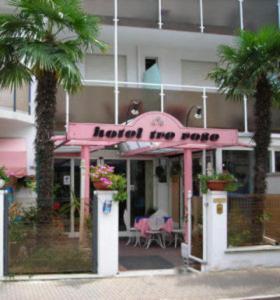 a pink restaurant with palm trees in front of a building at Hotel Tre Rose New 2026 in Riccione