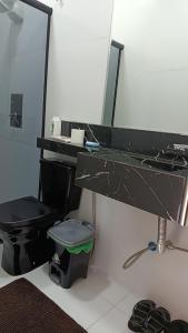 a bathroom with a black toilet and a mirror at Suíte caripi in Barcarena
