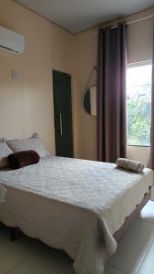 a bedroom with a large bed with a window at Suíte caripi in Barcarena