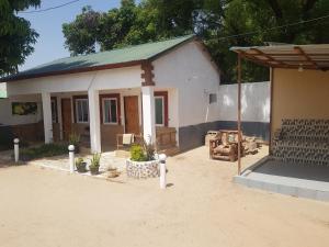 a small white house with a lot of plants in front at baobolong ghuesthouse in Lamin Koto