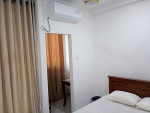 a bedroom with a bed and a window with a curtain at Eco Bliss Ragama in Ragama