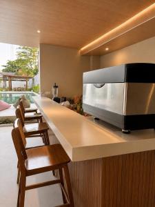 a kitchen with a counter with chairs and a microwave at Qwank Kuta Lombok in Kuta Lombok
