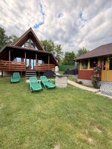 a group of green chairs in front of a house at Cabana A frame Casa Edy in Călimăneşti
