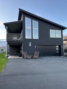 a black house with two chairs in front of it at Moderne enebolig med gratis parkering in Alta