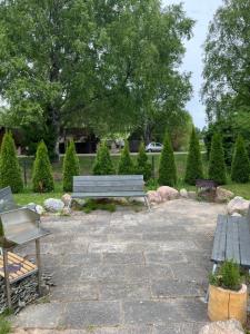 two park benches sitting on a stone patio at Albatross Seaside Escape in Ķesterciems +7 photos