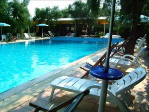 a swimming pool with chairs and an umbrella at Vieste Residence Gallo Con Piscina in Vieste