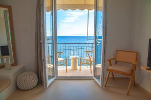 a room with a balcony with a view of the ocean at To Nisi in Loutraki
