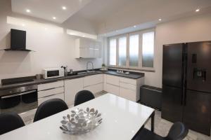 a kitchen with a table and a black refrigerator at La Galleria Milano - 160 sqm Design Apartment, Spa & Parking in Milan