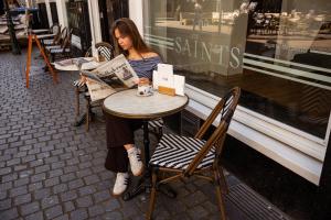 een vrouw die aan een tafel voor een winkel zit bij The Saints Sutor Hotel in Breda