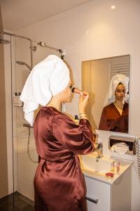 een vrouw staat in een badkamer haar tanden te poetsen bij The Saints Sutor Hotel in Breda +13 foto's
