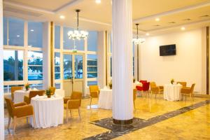 ein Festsaal mit Tischen, Stühlen und Fenstern in der Unterkunft LEBENE Hotel in Lomé