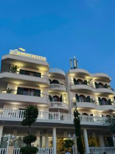 a large white building with trees in front of it at Lùmar Hotel in Vlorë