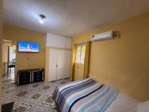 a bedroom with a bed and a tv on the wall at Guest House A&H - Boca Chica Beach & Airport in Boca Chica
