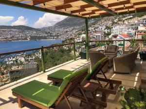 a balcony with chairs and tables and a view of a city at Villa Grande Kalkan in Kaş