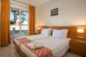 a hotel room with two beds and a window at Perla Marina Hotel in Ialysos +139 photos