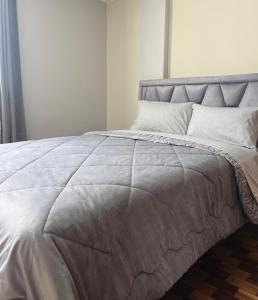 a bed with a gray blanket on top of it at Centrica y Residencial in Ambato