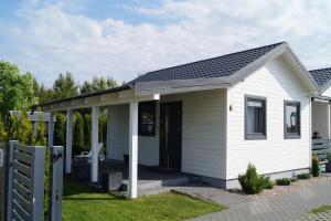 a small white house with a porch at SŁONECZNE DOMKI in Gąski