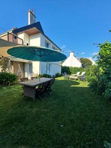 a picnic table with an umbrella in a yard at logement avec jardin de bord Mer PORT NAVALO in Arzon