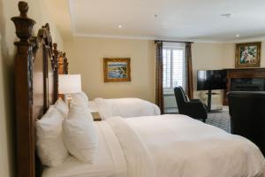a bedroom with a large white bed and a television at Riverbend Inn & Vineyard in Niagara-on-the-Lake