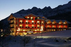 a large building with christmas lights in the snow at Hotel Continental in Andalo