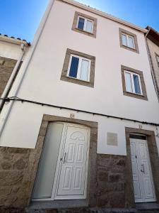 a white building with two doors and windows at Casa Bossa Nova in Fundão